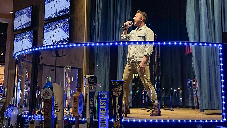 Man singing on stage with a microphone in center of the casino.